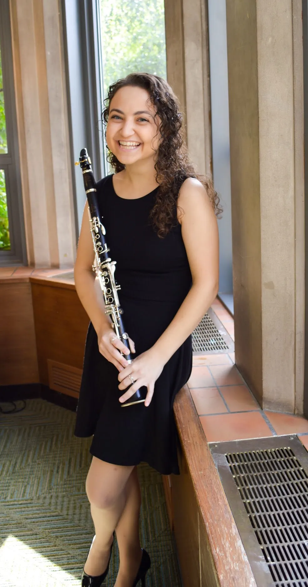 valerie in a black dress holding her clarinet and smiling